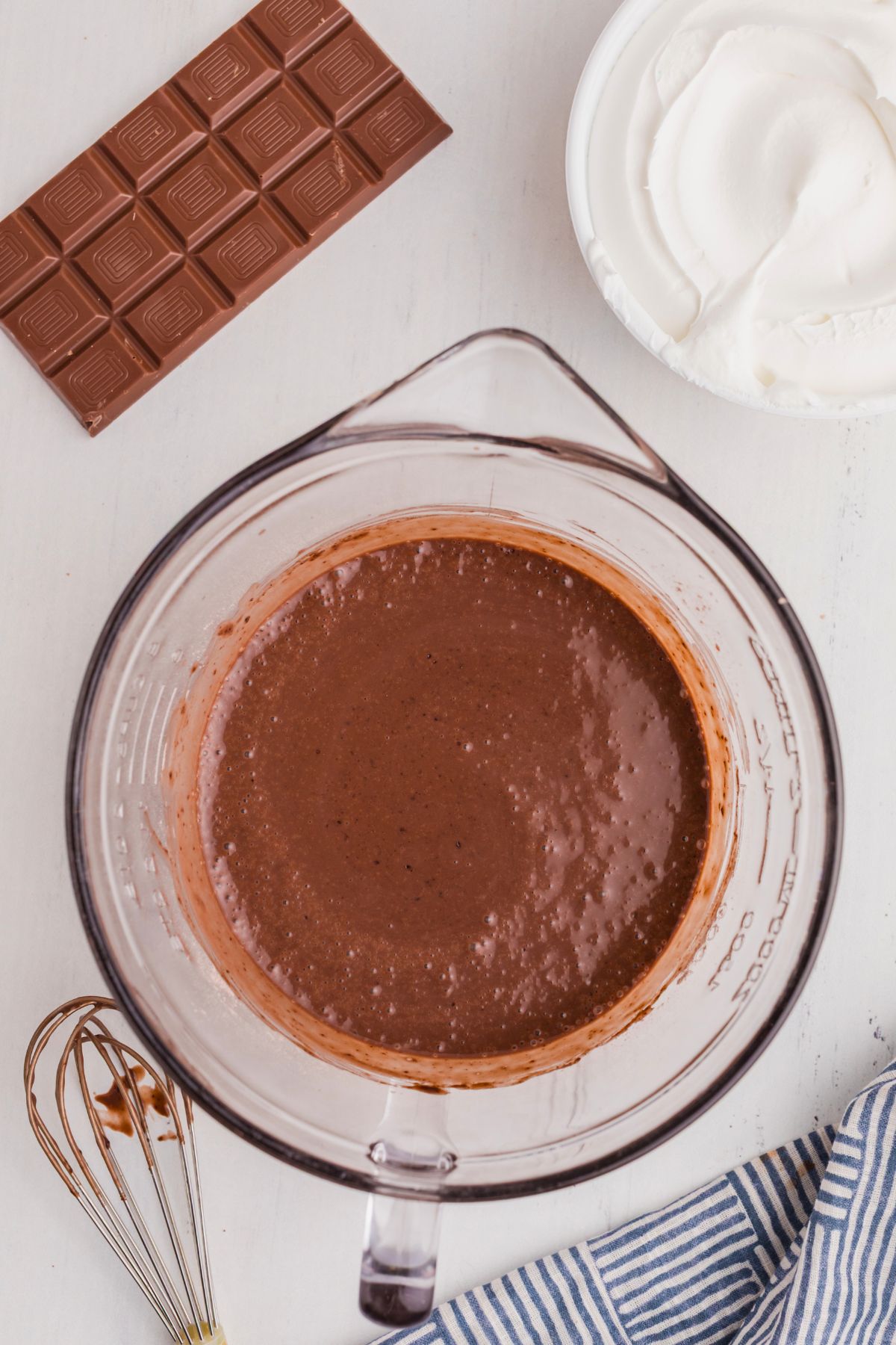 Chocolate cake mix batter mixed in a clear glass bowl on a white marble table.