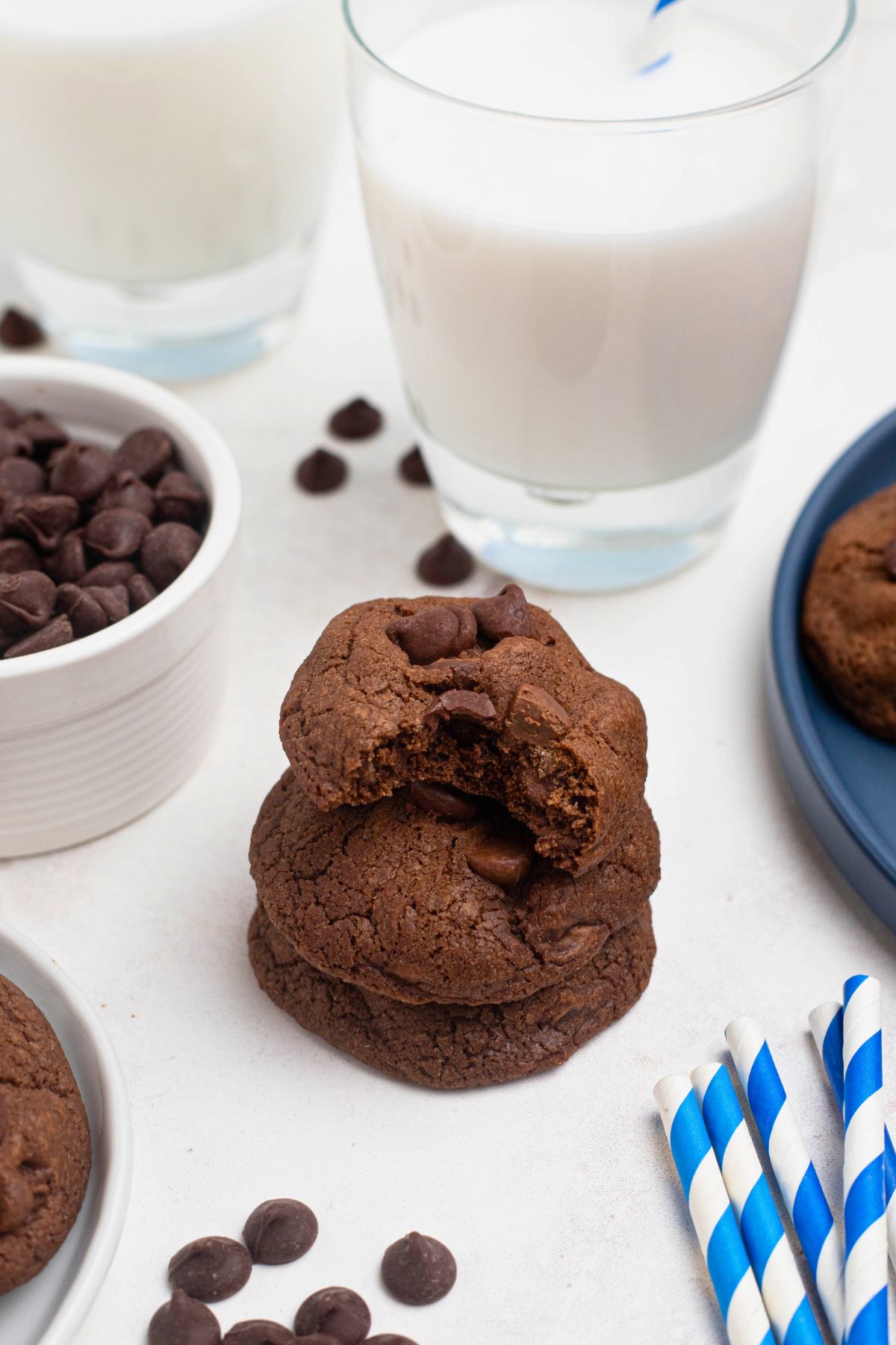 Double chocolate chip cookies stacked on a marble table in front of glass of milk. 