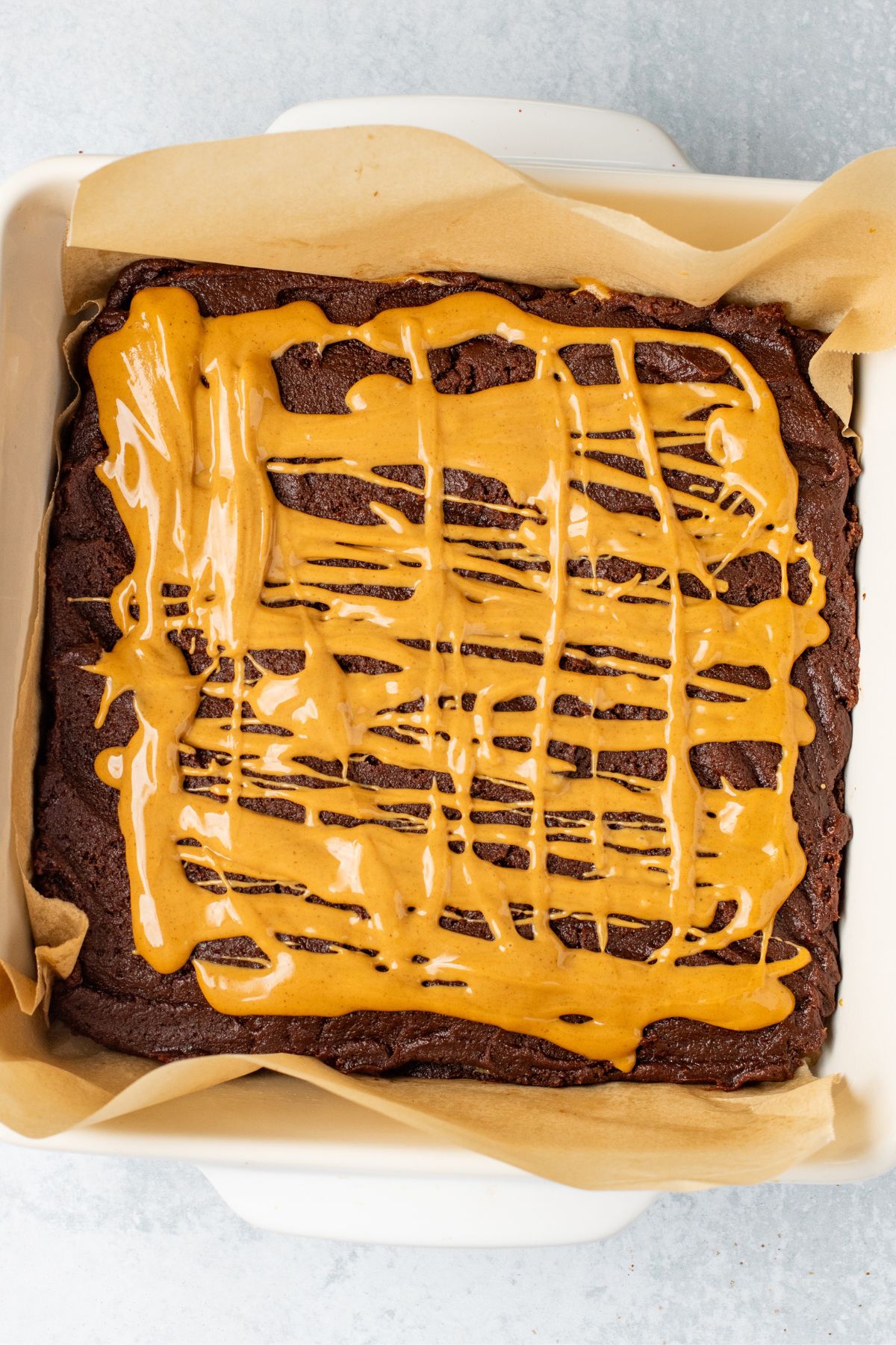 Chocolate brownie batter, topped with peanut butter filling in an 8x8 baking dish. 