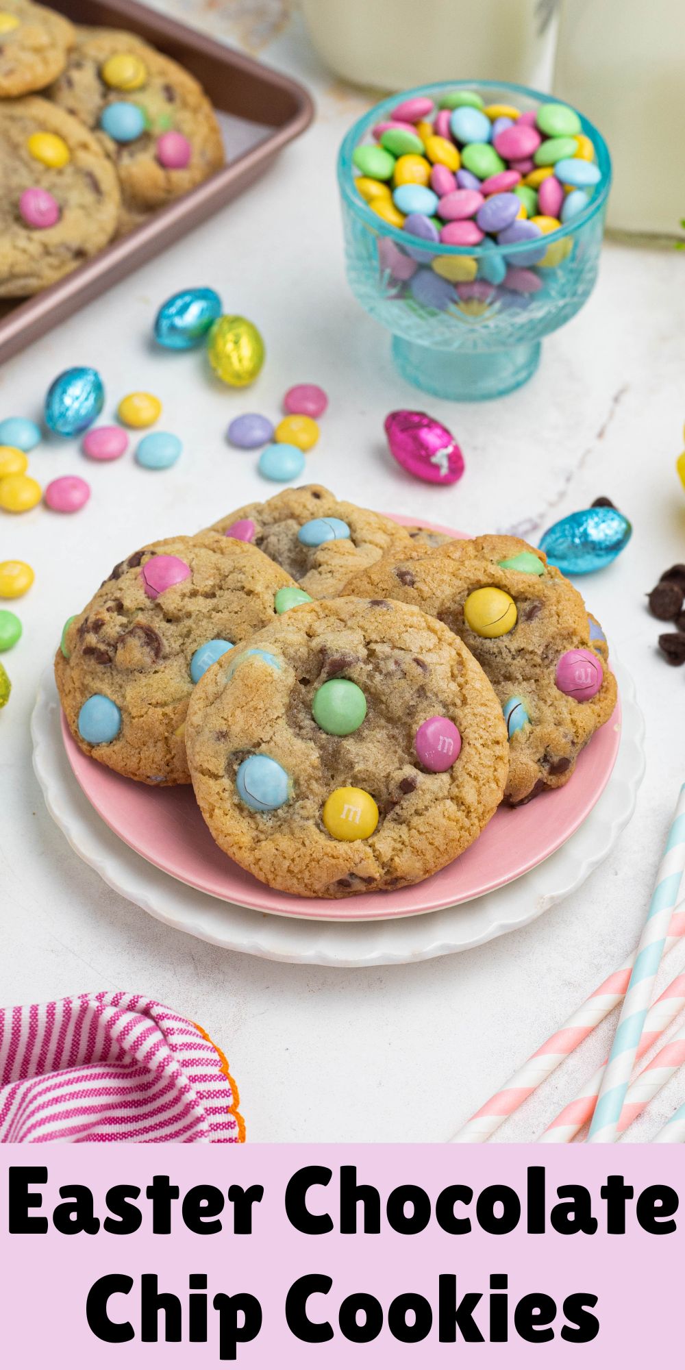 Golden chocolate chip cookies with pastel candies on plates, in front of candy dish and glasses of milk.