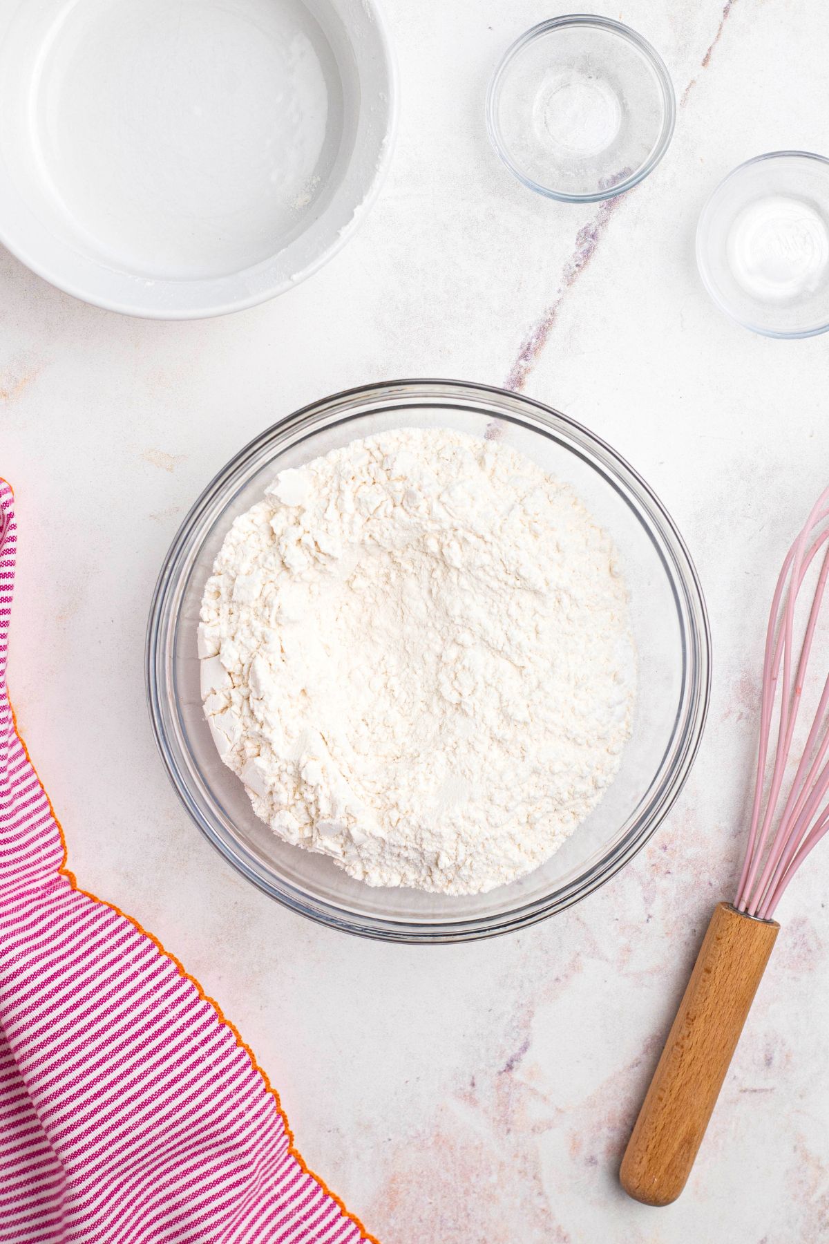 Flour and other dry ingredients mixed in a clear glass bowl.