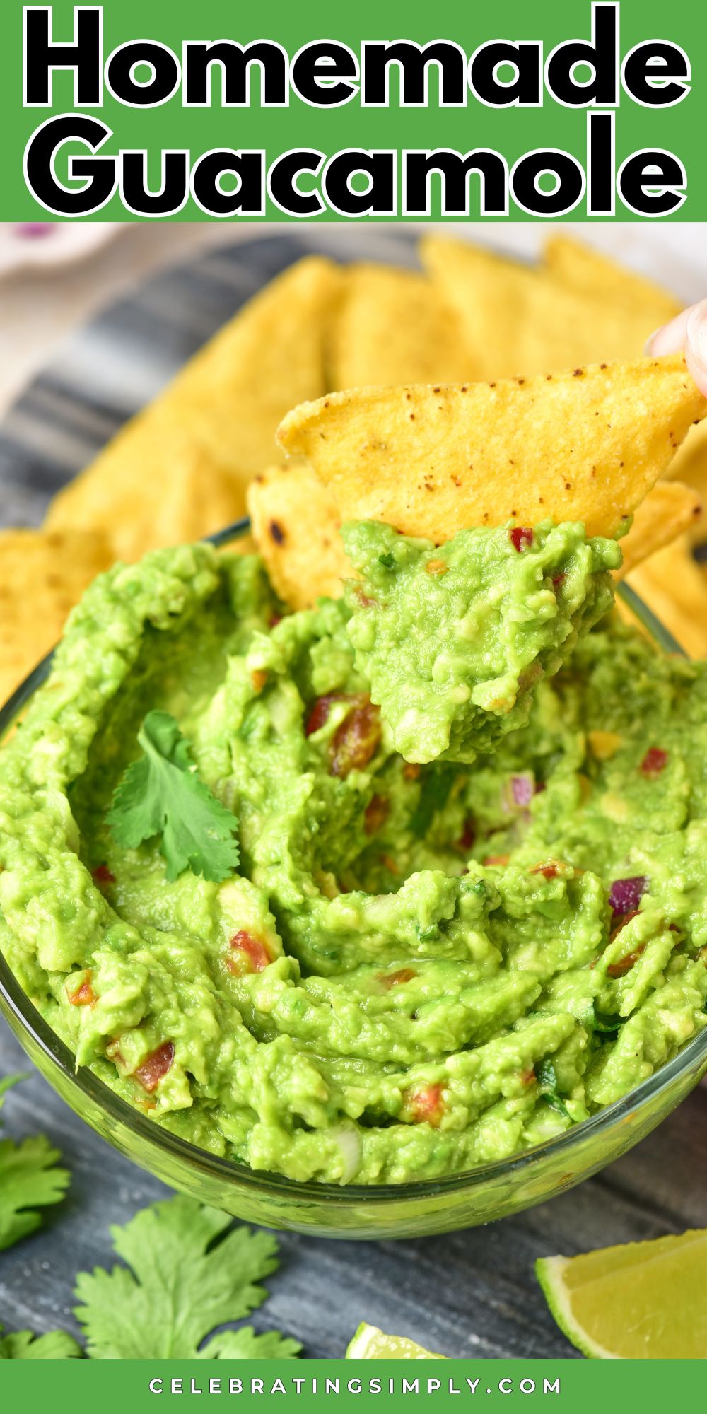 Creamy guacamole with chopped tomatoes and onions mixed in it, with tortilla chip being dipped into the bowl.