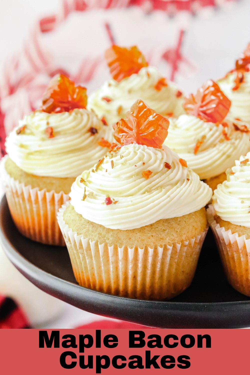 Frosted cupcakes on a black stand with crumbled bacon sprinkled on top.