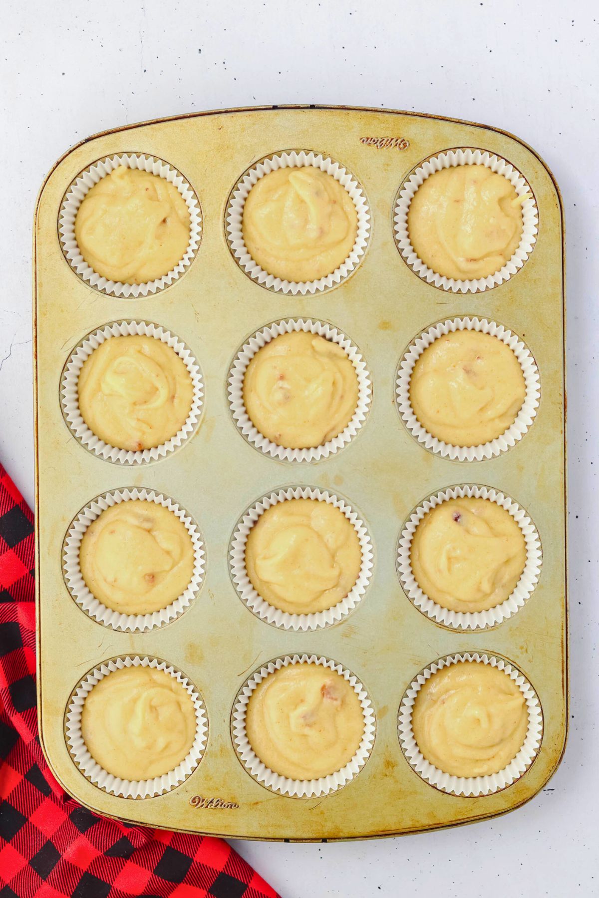 Cupcake batter poured into liners in a baking pan before baking. 