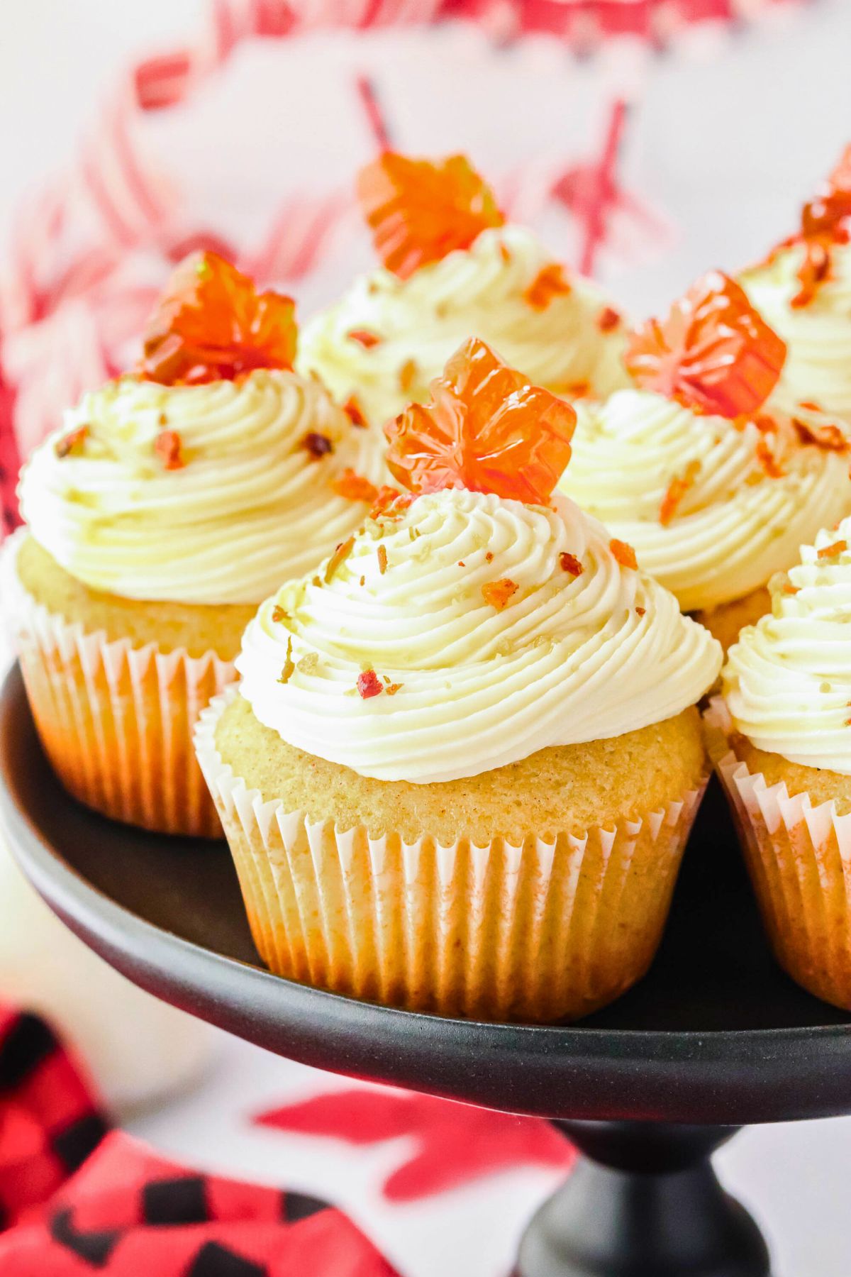 Golden cupcakes on a black stand with crispy bacon crumbled on top. 