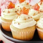 Frosted cupcakes on a black stand with crumbled bacon sprinkled on top.