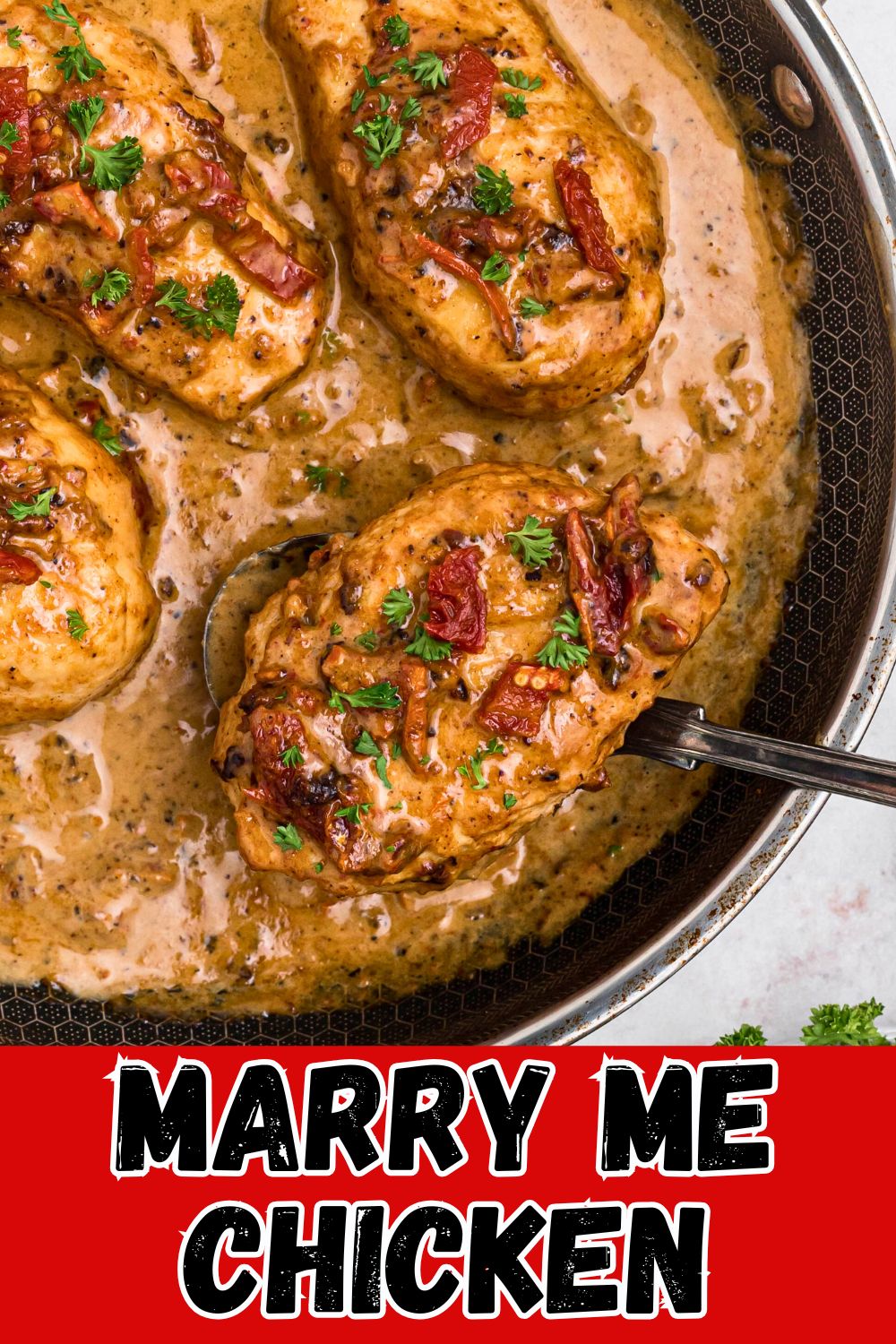 Creamy chicken in a large skillet with a spoon lifting a piece out of skillet.