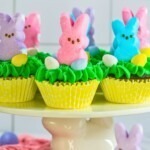 Peeps cupcakes with pastel bunnies on top of a cake stand.
