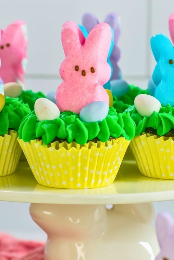 Peeps cupcakes with pastel bunnies on top of a cake stand.
