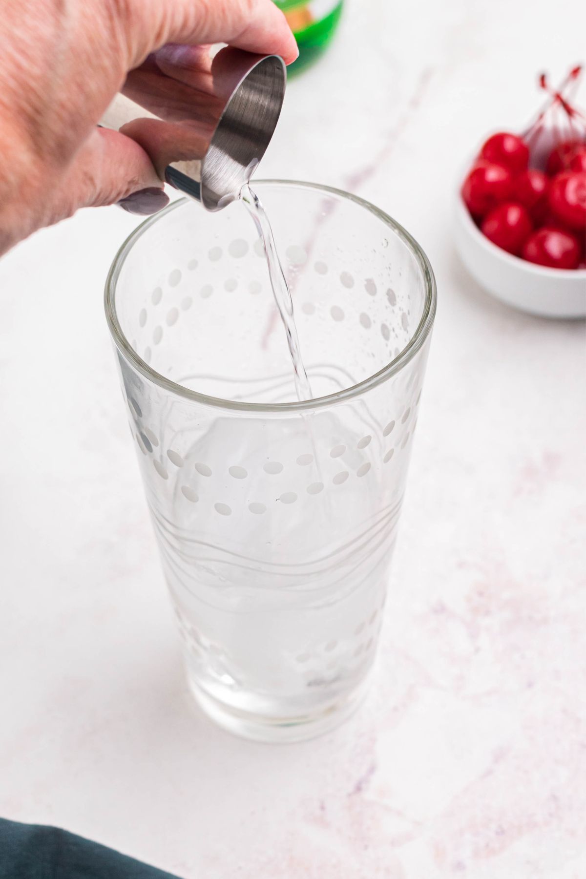 Rum being poured into clear glass cocktail shaker. 