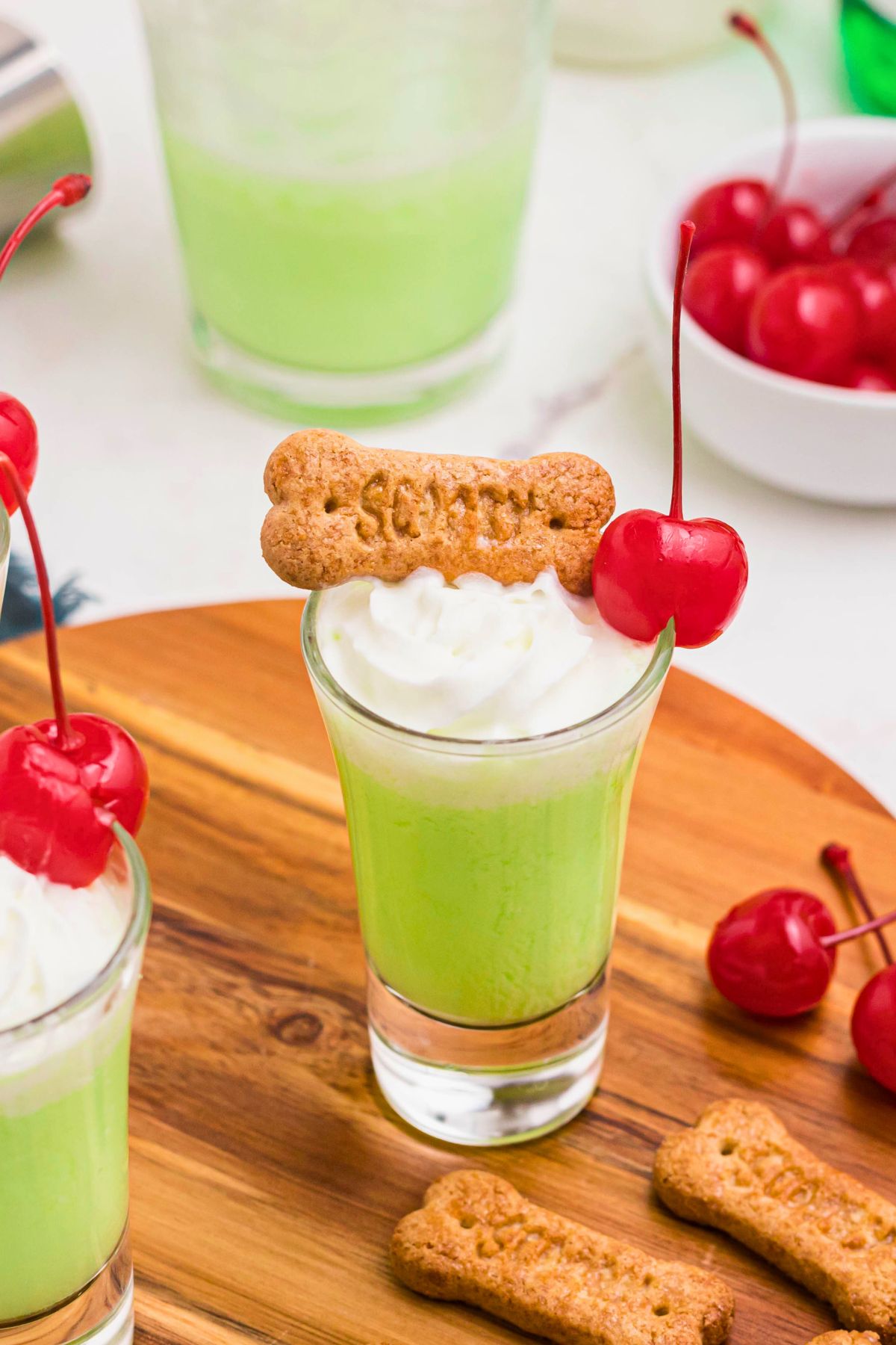 Green shot in a shot glass topped with a cherry and whipping cream. 