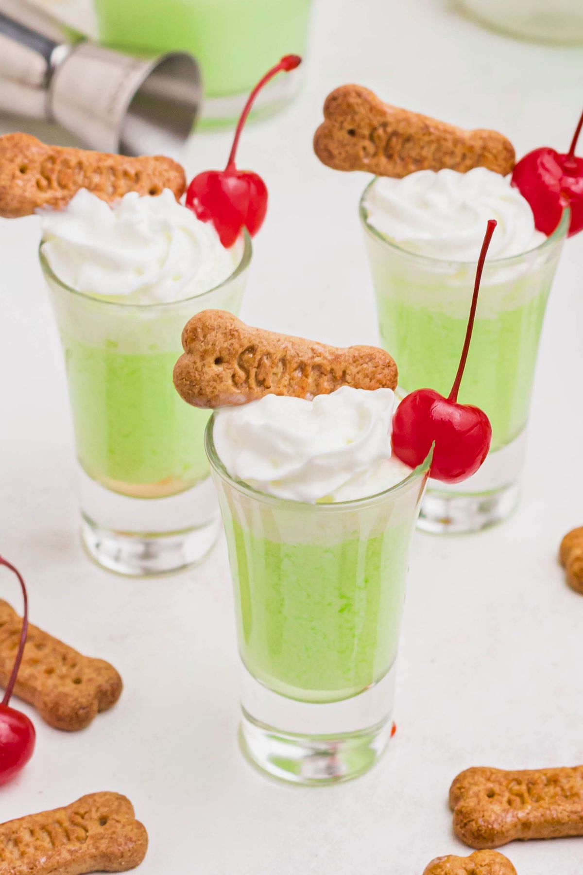 Green scooby snack shot in a small glass, topped with whipping cream and a cherry. 