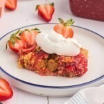 Golden cake crumble on strawberry pie filling on a white plate.