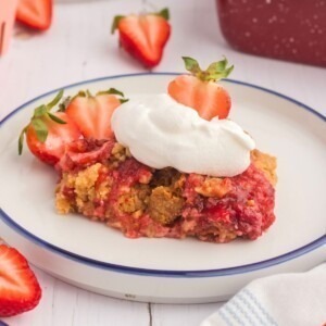 Golden cake crumble on strawberry pie filling on a white plate.