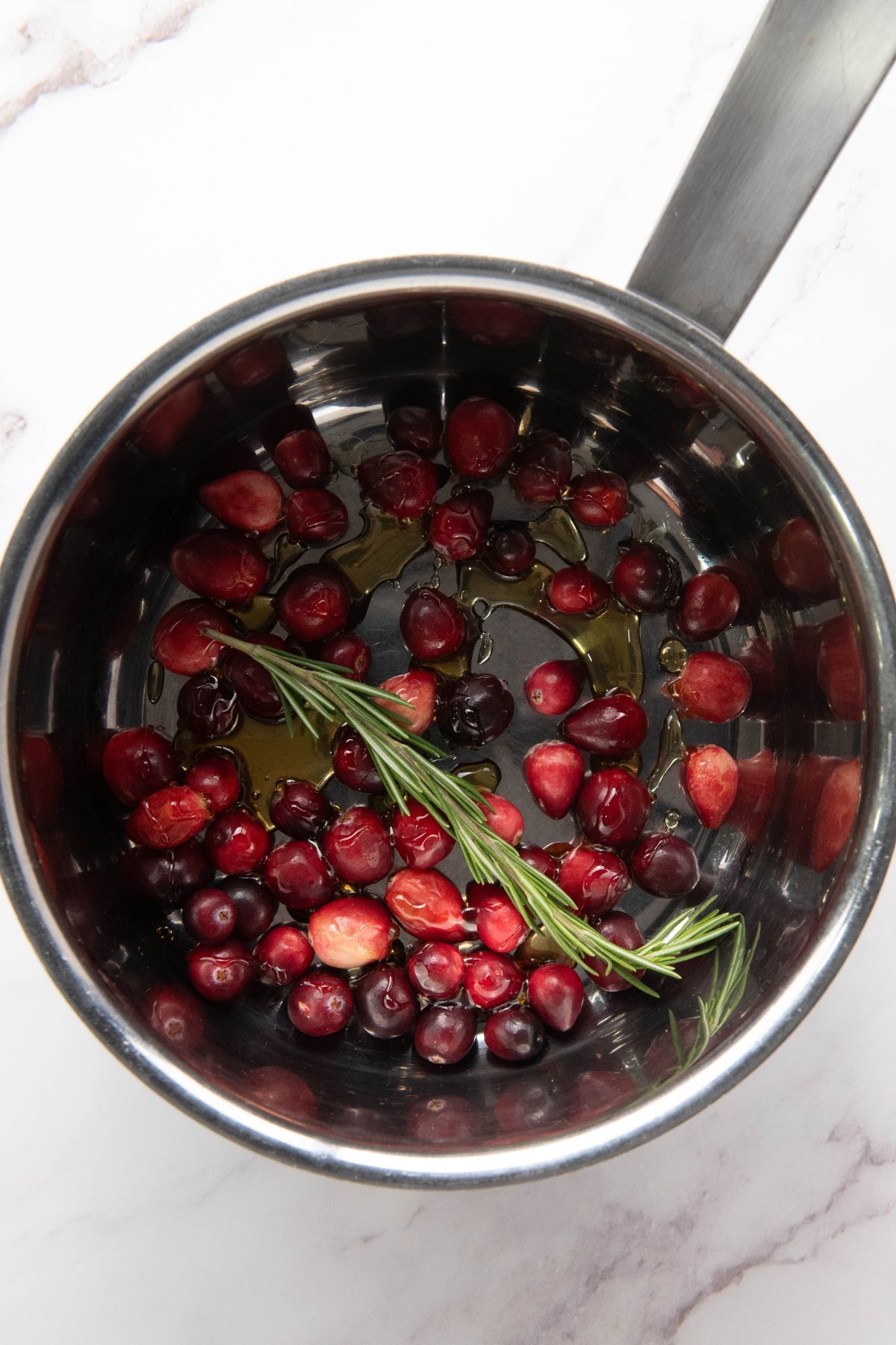 Cranberries, sugar, and other ingredients being cooked in a small saucepan.