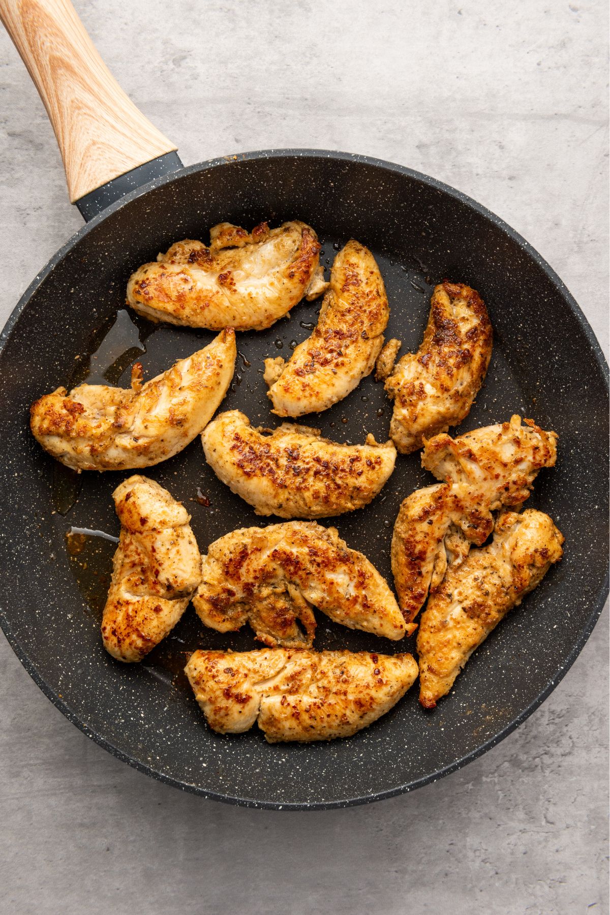 Seasoned chicken in a skillet after being seared. 