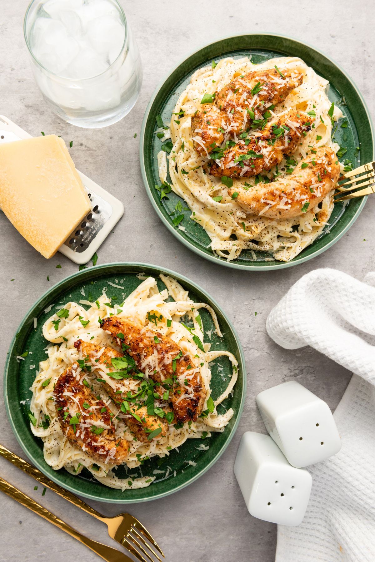 Cajun chicken on top of fettuccini alfredo on green plates. 