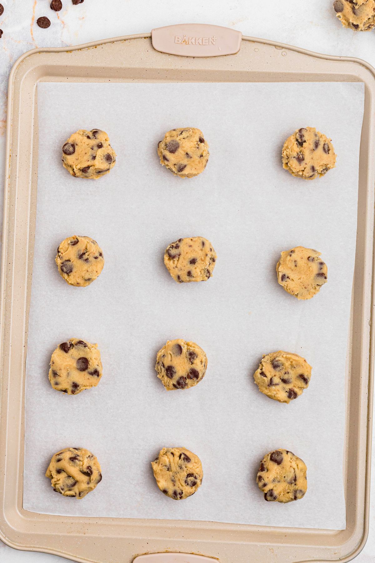 Cookie dough in small balls on a baking sheet lined with parchment paper. 