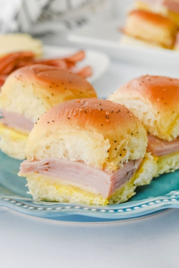 Rolls filled with ham and cheese slices on a blue plate.