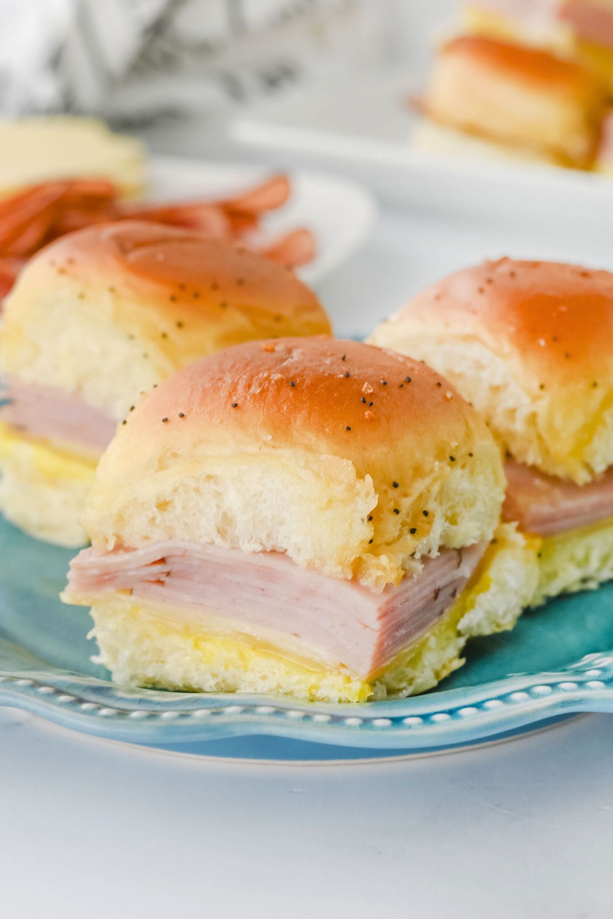 Rolls filled with ham and cheese slices on a blue plate.