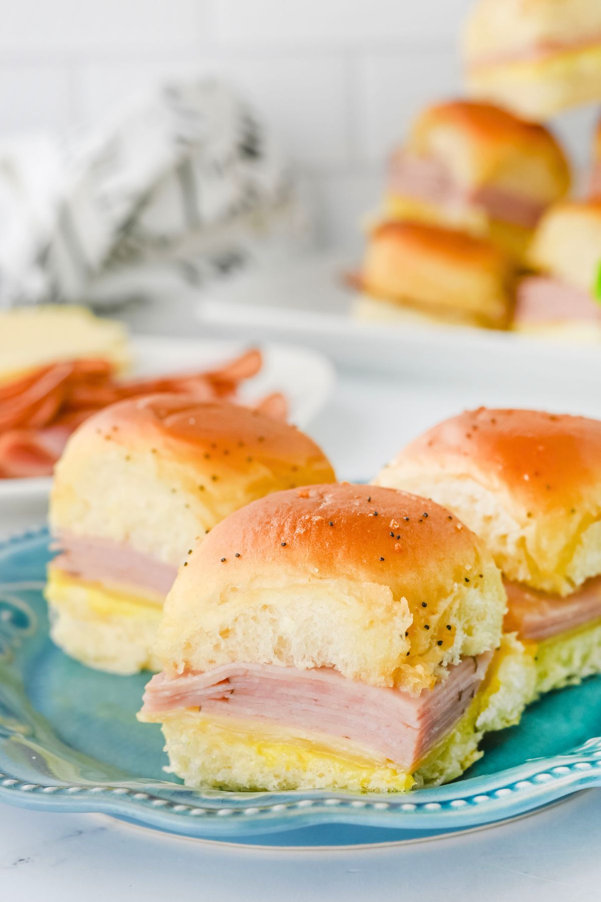Rolls filled with ham and cheese slices on a blue plate.