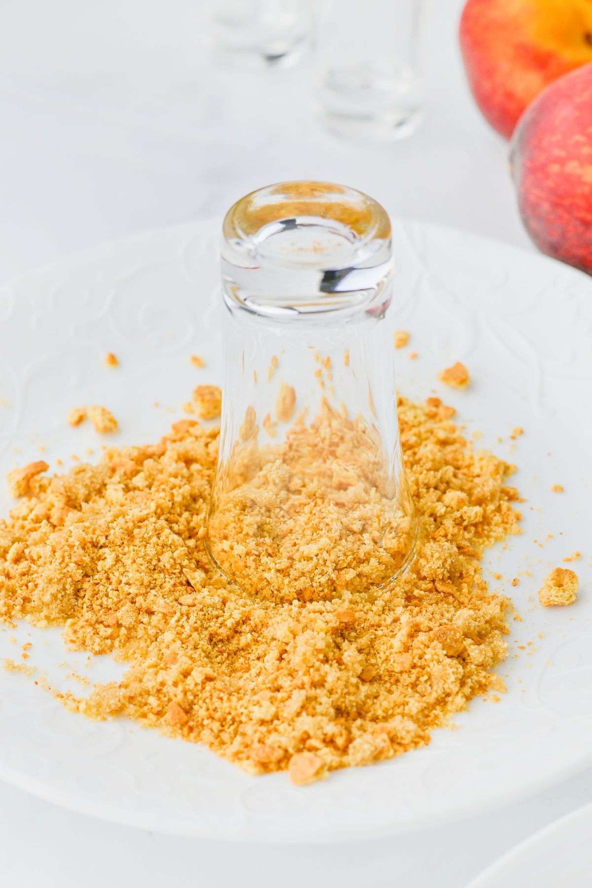 Shot glass being dipped into graham cracker crumbs to line the rim. 
