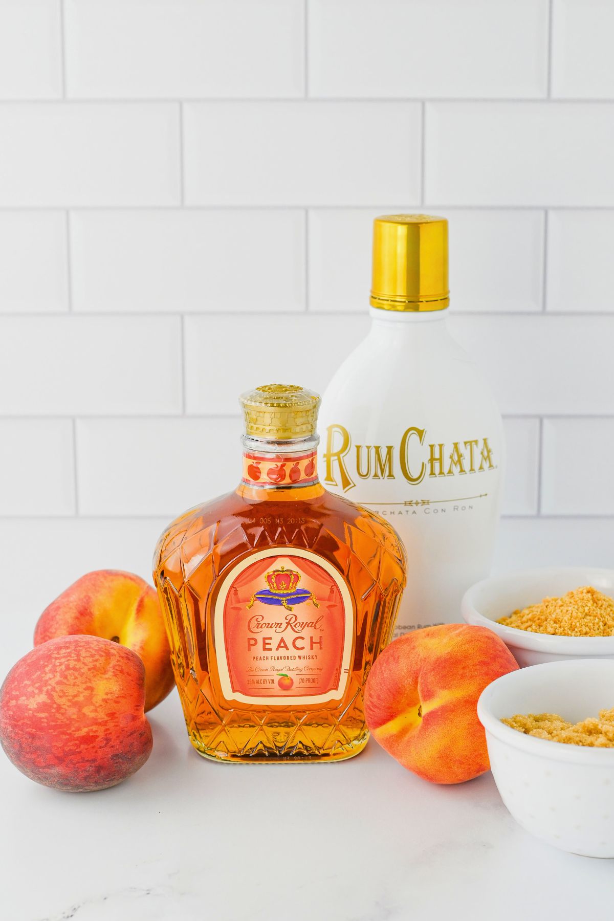 Ingredients needed to make a peach cobbler shot on a marble table. 