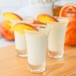 Small shot glasses filled with drinks, then garnished with peach slices.