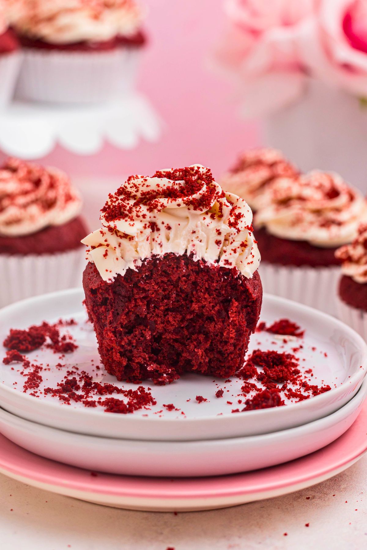 Bright red cupcakes with a small part cut aside showing the texture. 