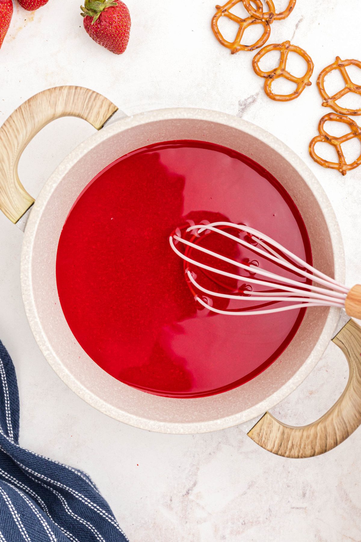 Strawberry Jell-o being mixed with boiling water in a saucepan.