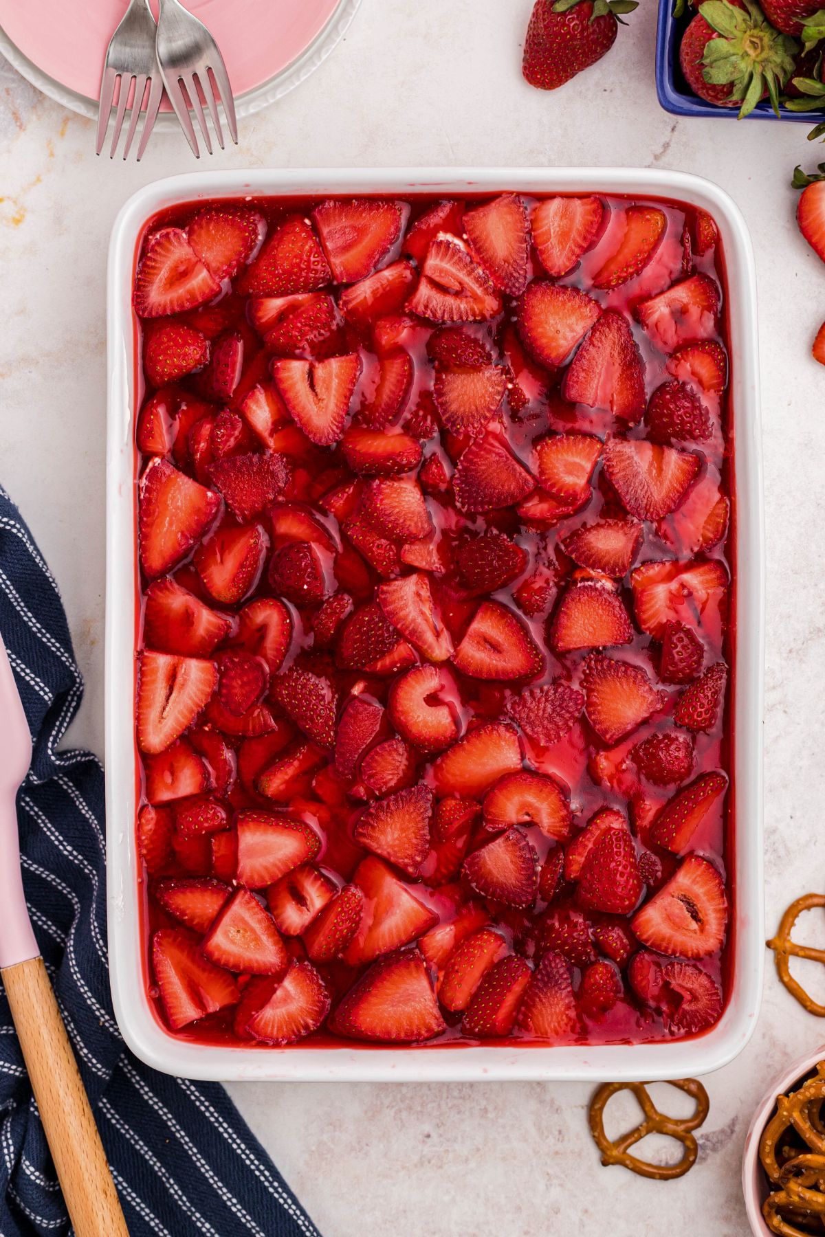 White baking dish filled with crust, strawberries, and j-ello topping.