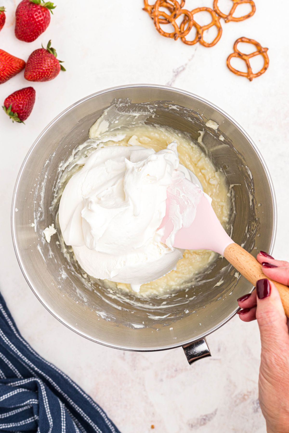 Cream cheese, sugar, and cool whip mixed together in a silver bowl.
