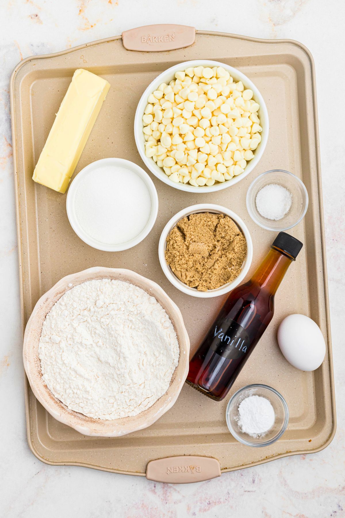 Ingredients needed to make white chocolate chip cookies, measured and put into small bowls. 