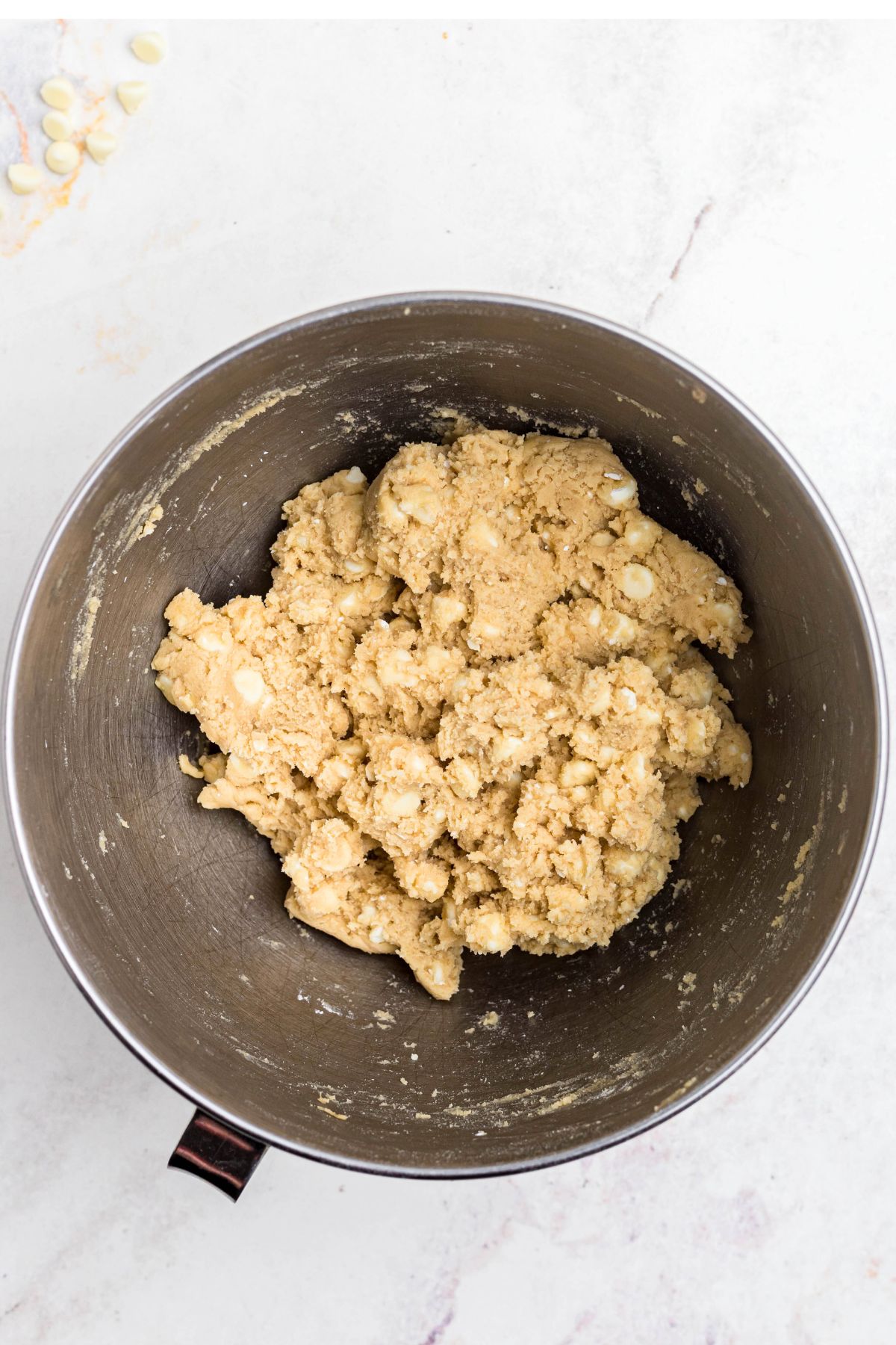 Dough mixed in a bowl with white chips. 