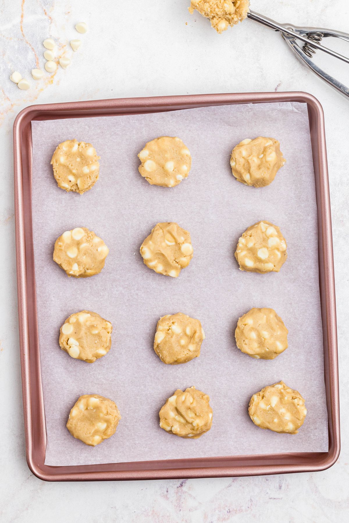 Uncooked cookie dough in small balls on a pink baking sheet. 