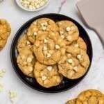 Golden white chocolate chip cookies on a black plate