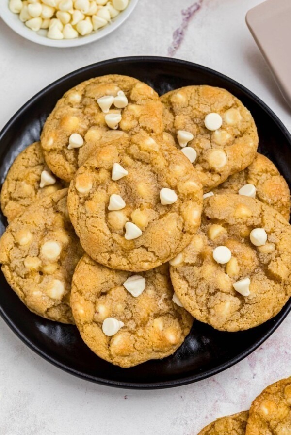 Golden white chocolate chip cookies on a black plate