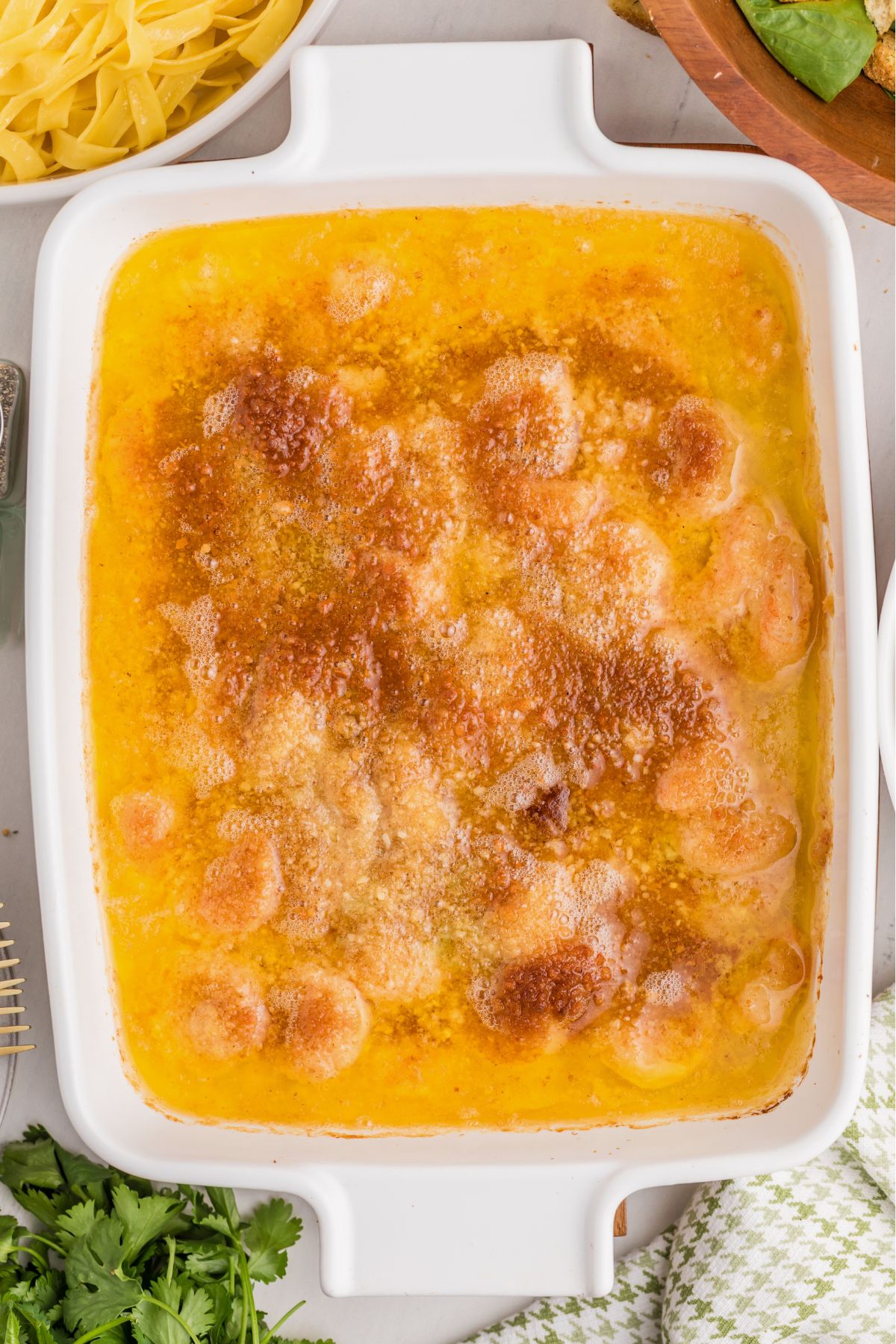 Baked, cheesy shrimp scampi in a white baking dish.