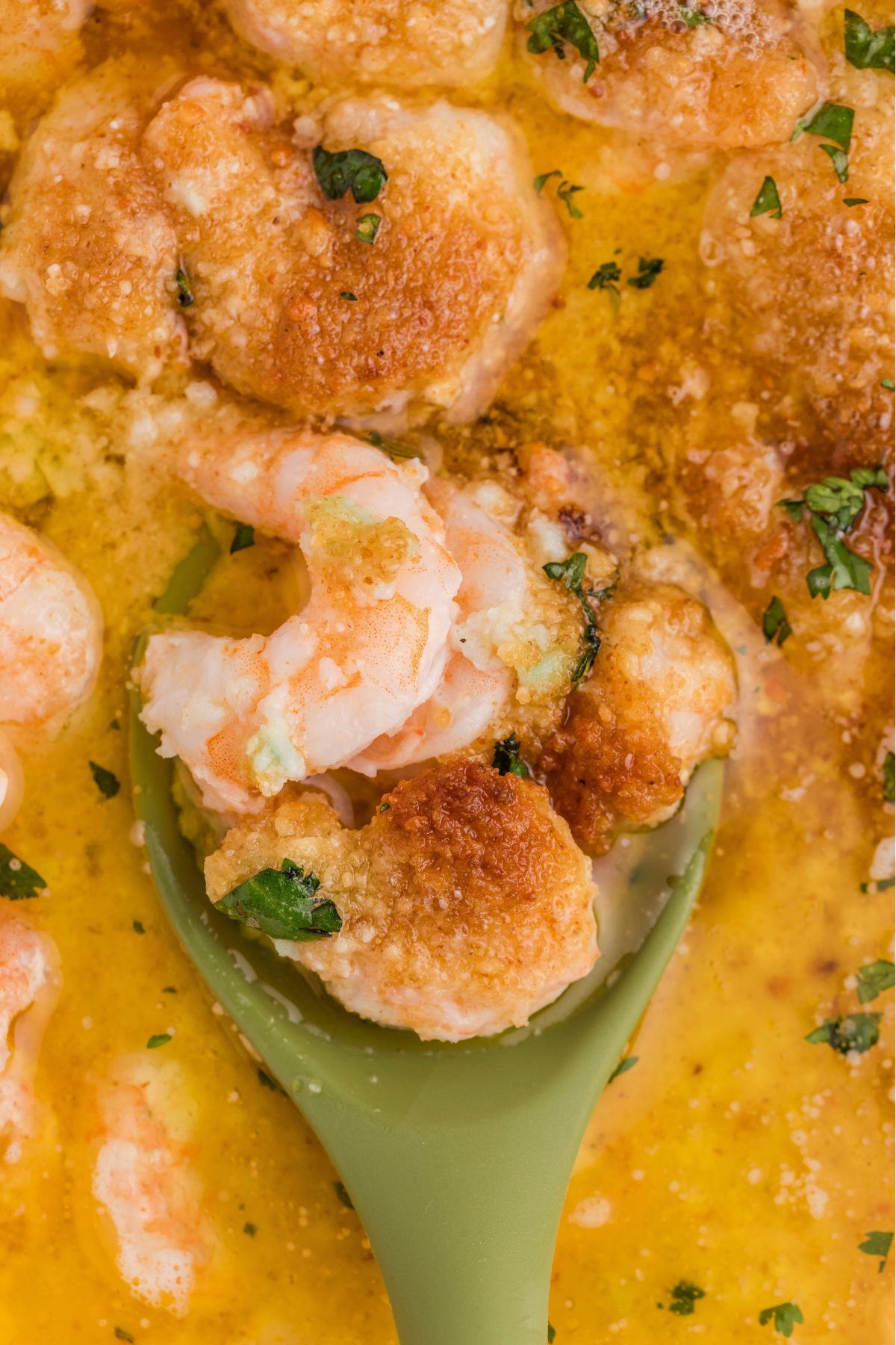 Spoonful of shrimp being scooped out of baking dish.
