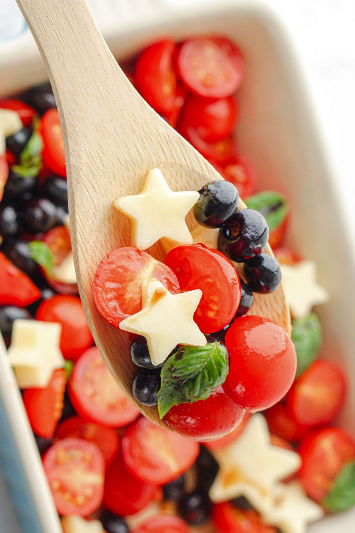 Spoonful of berries, tomatoes, and stars on a wooden spoon. 