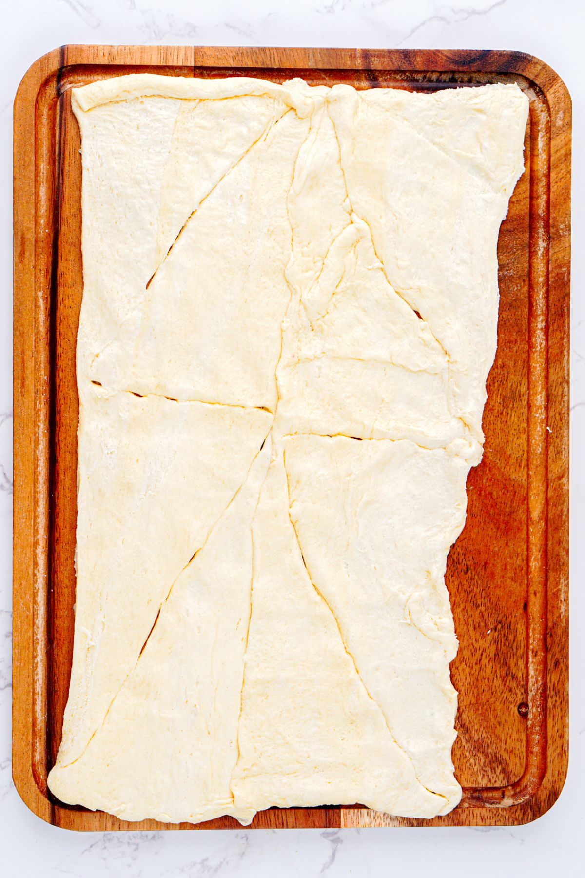 Crescent dough unrolled on a baking sheet. 