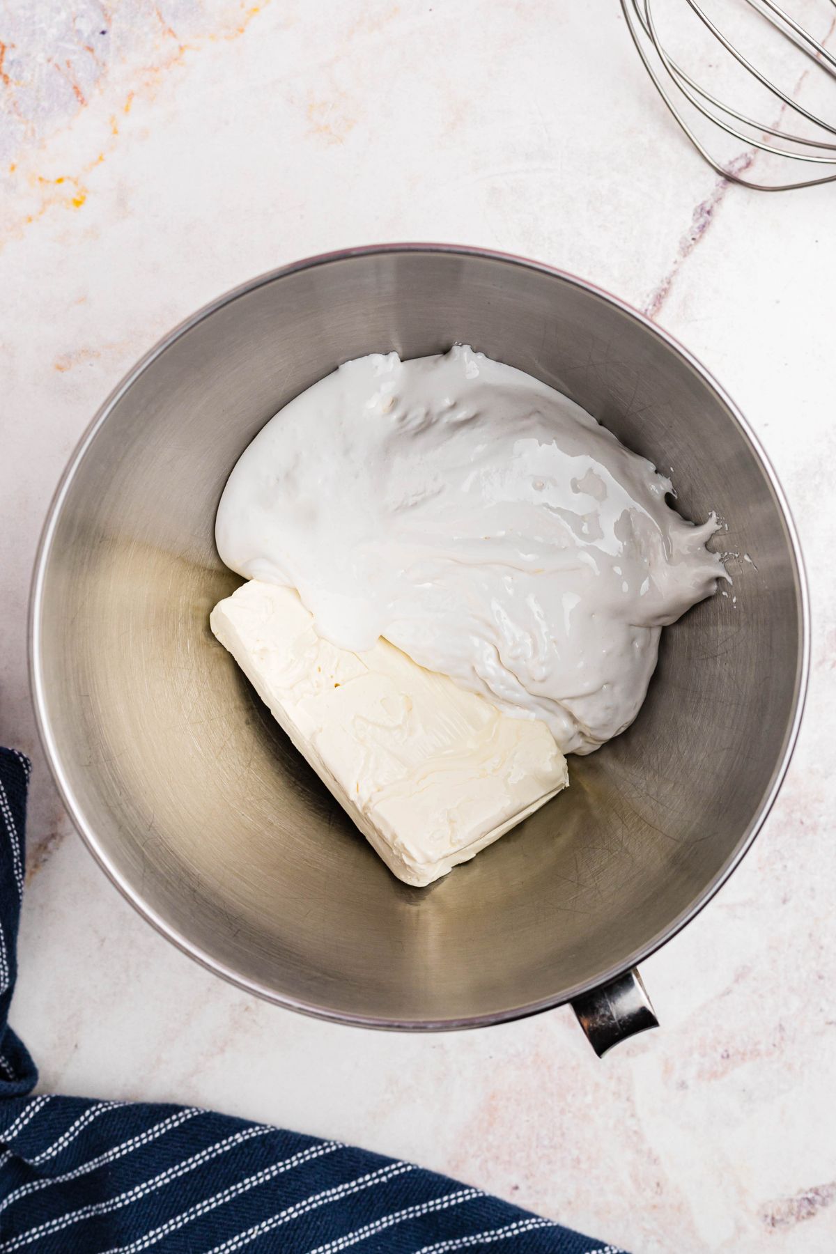 A block of cream cheese and marshmallow creme in a silver mixing bowl. 