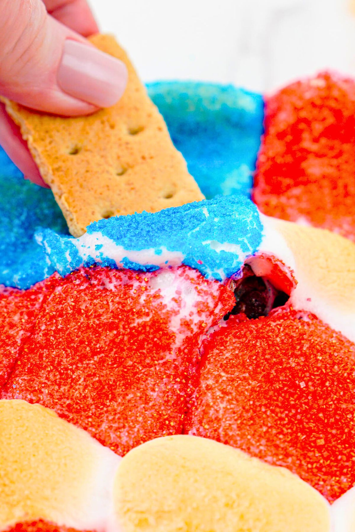 Graham cracker being dipped into melted marshmallows.