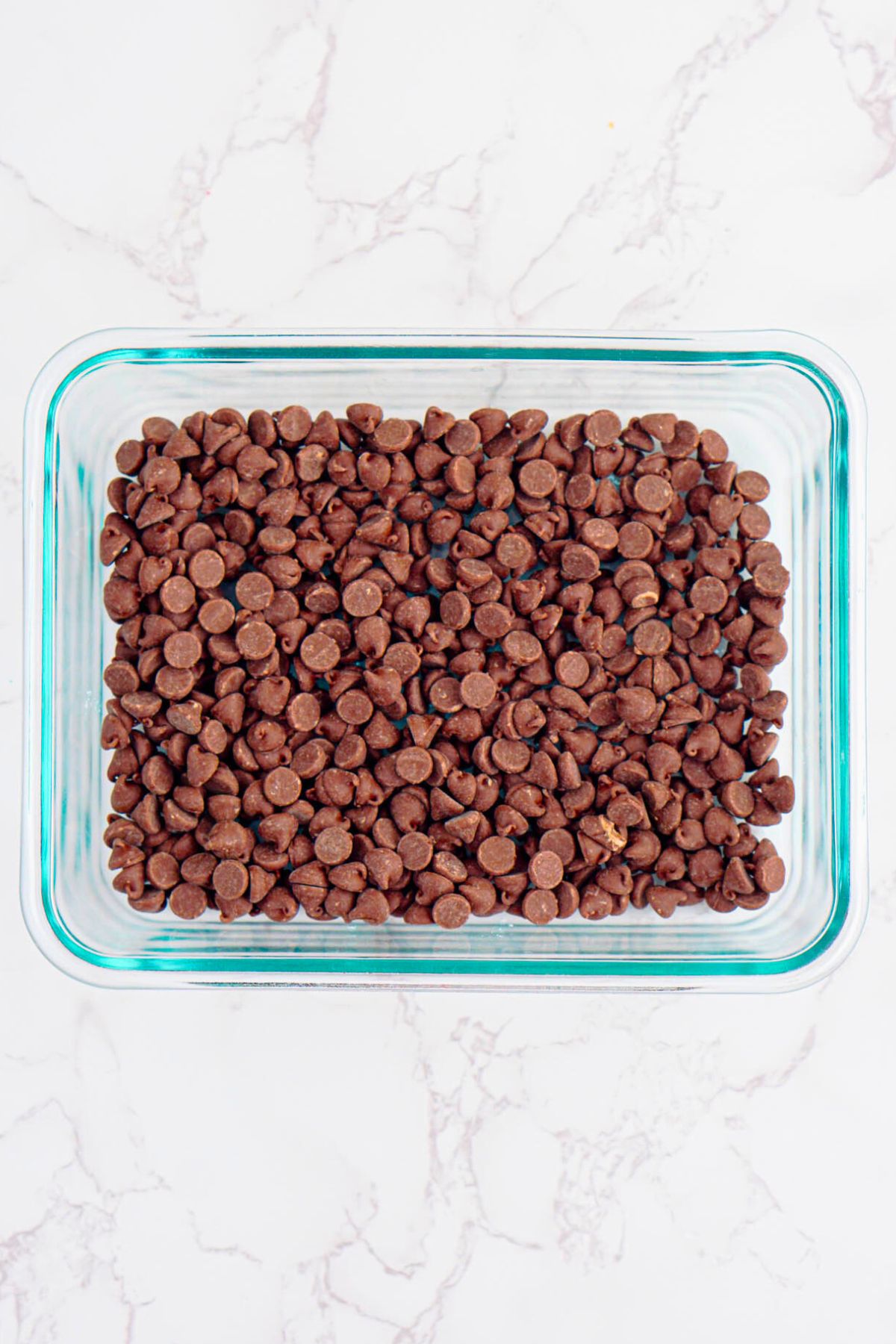 Chocolate chips spread evenly in a clear baking dish.