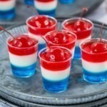 Layered jello in small shot glasses on silver plates.
