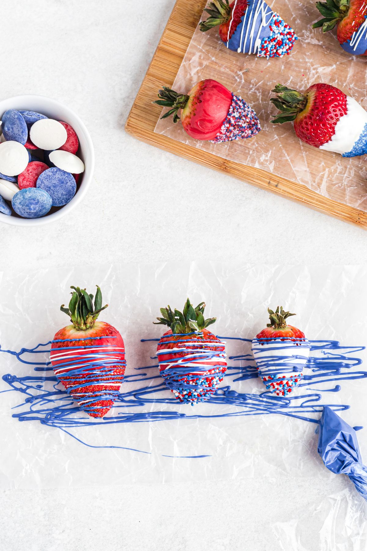 Dipped berries being decorated with drizzles of red, white, and blue candy melts. 