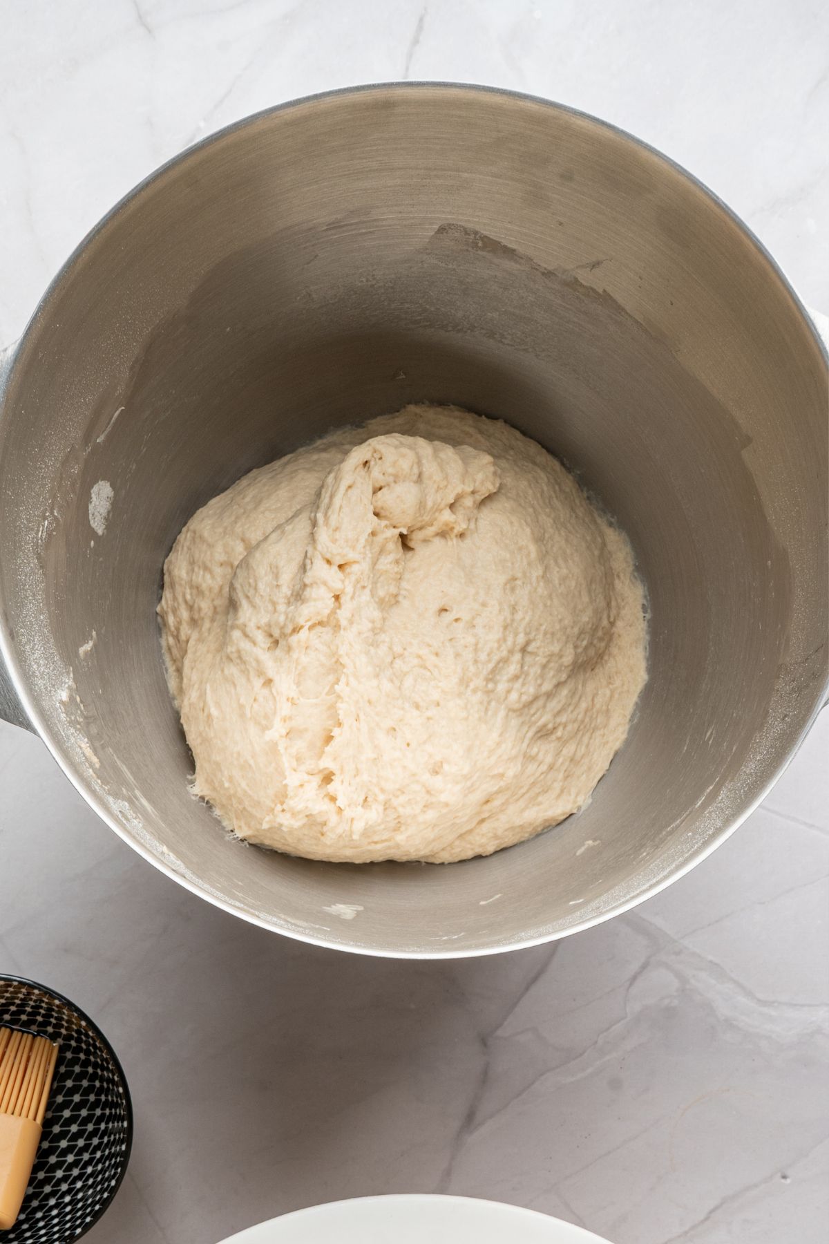 Bread dough in a silver mixing bowl, waiting for dough to rise. 