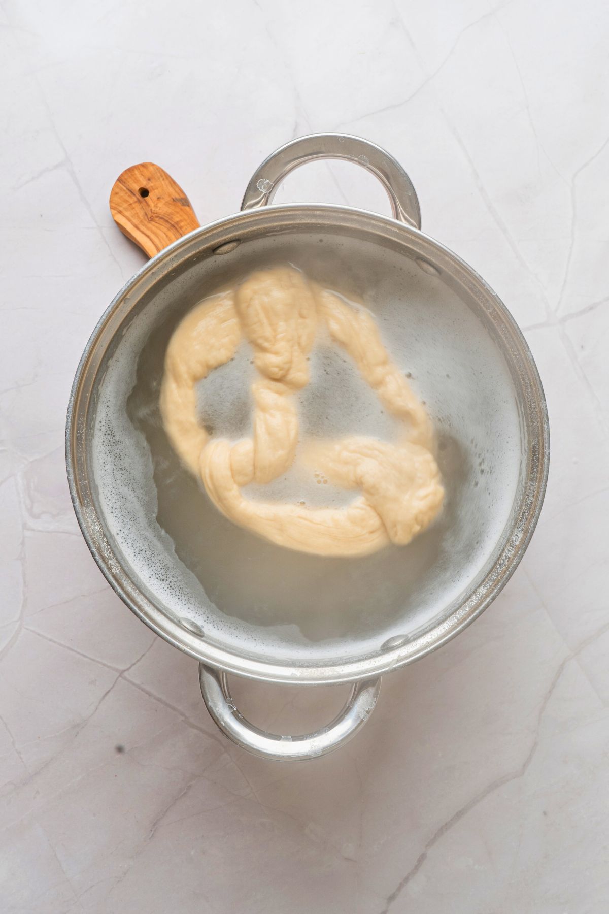 Pretzels being boiled in baking soda water bath before being baked. 