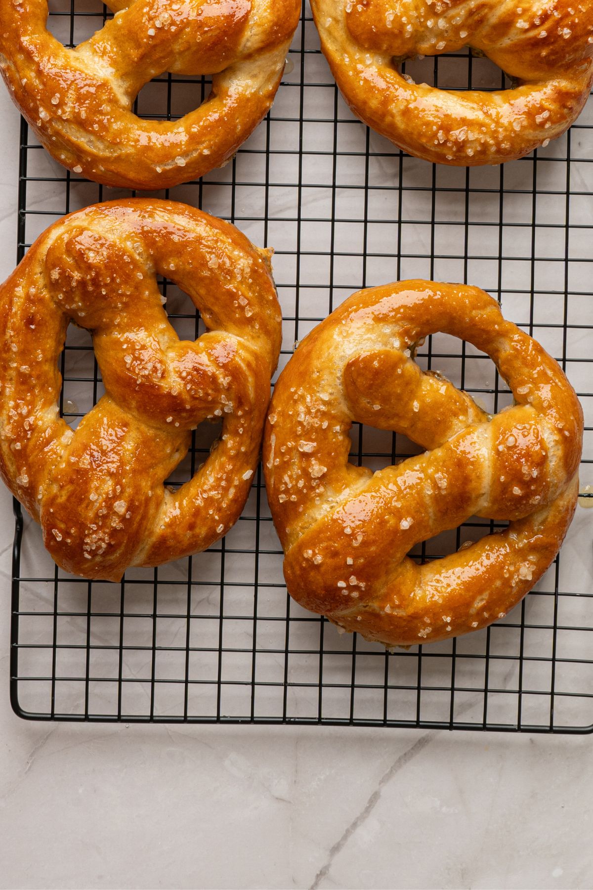 Baked golden pretzels on a wire rack on a marble table. 