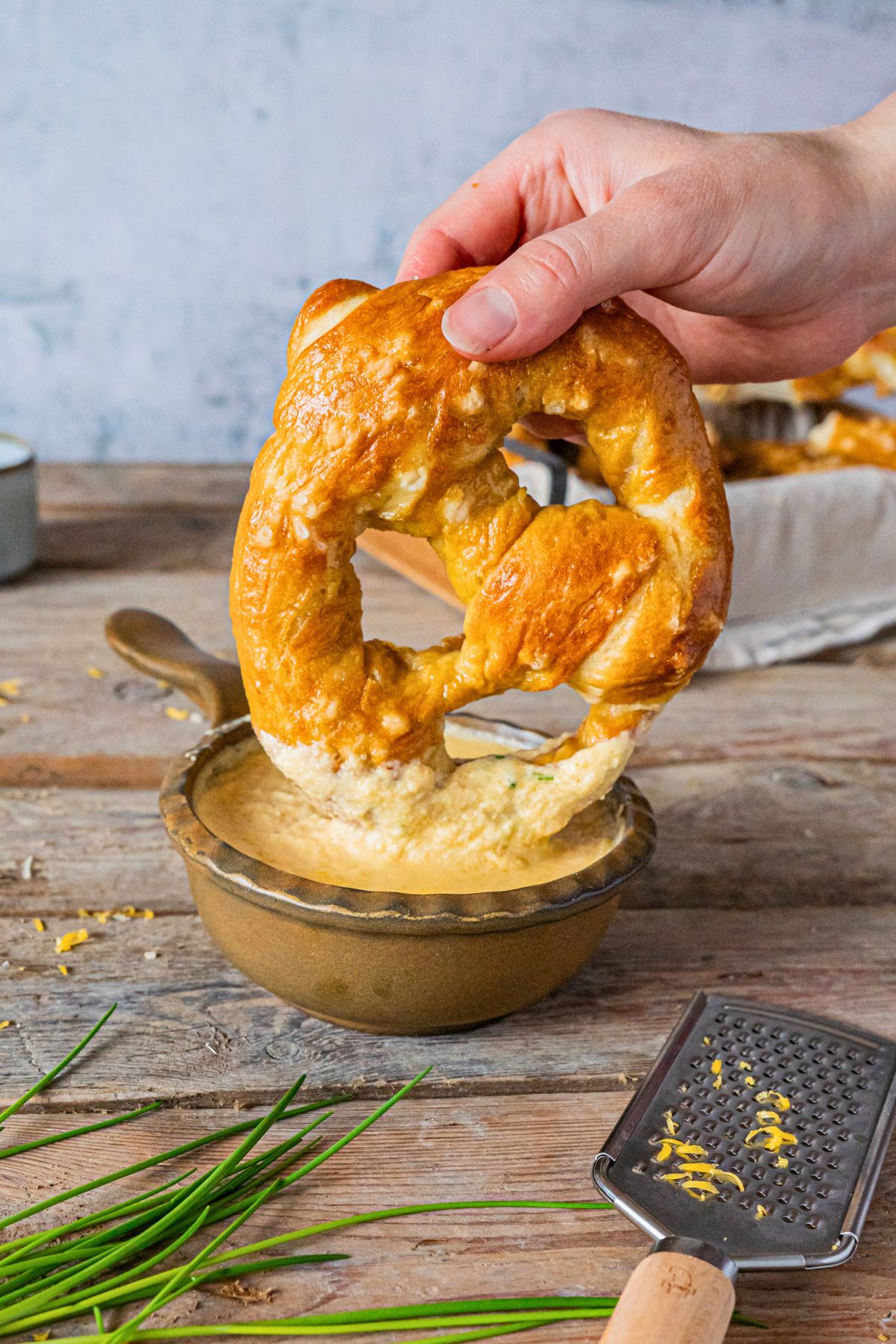Soft golden pretzel being dipped into melted beer cheese. 